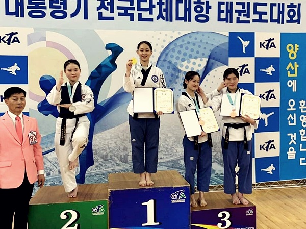 ▲ 김아름(1학년) 선수(가운데)가 우승 메달을 들어보이고 있다. (사진 고신대 제공)